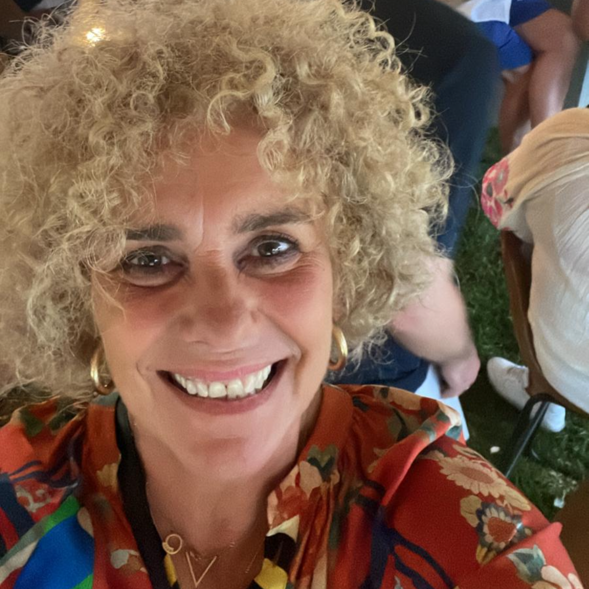 Woman with curly blonde hair smiling at a social gathering